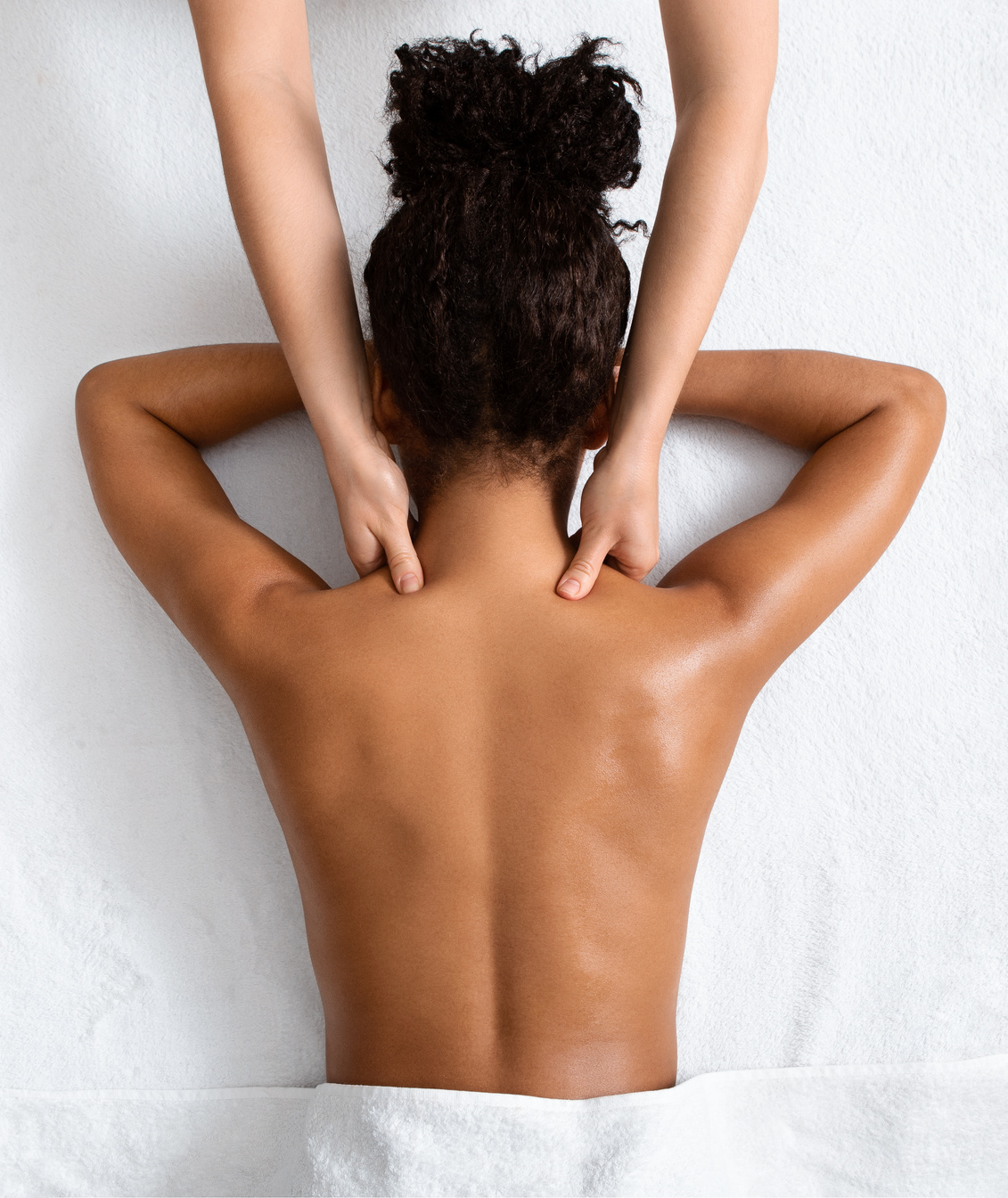 Female therapist massaging black woman neck, top view